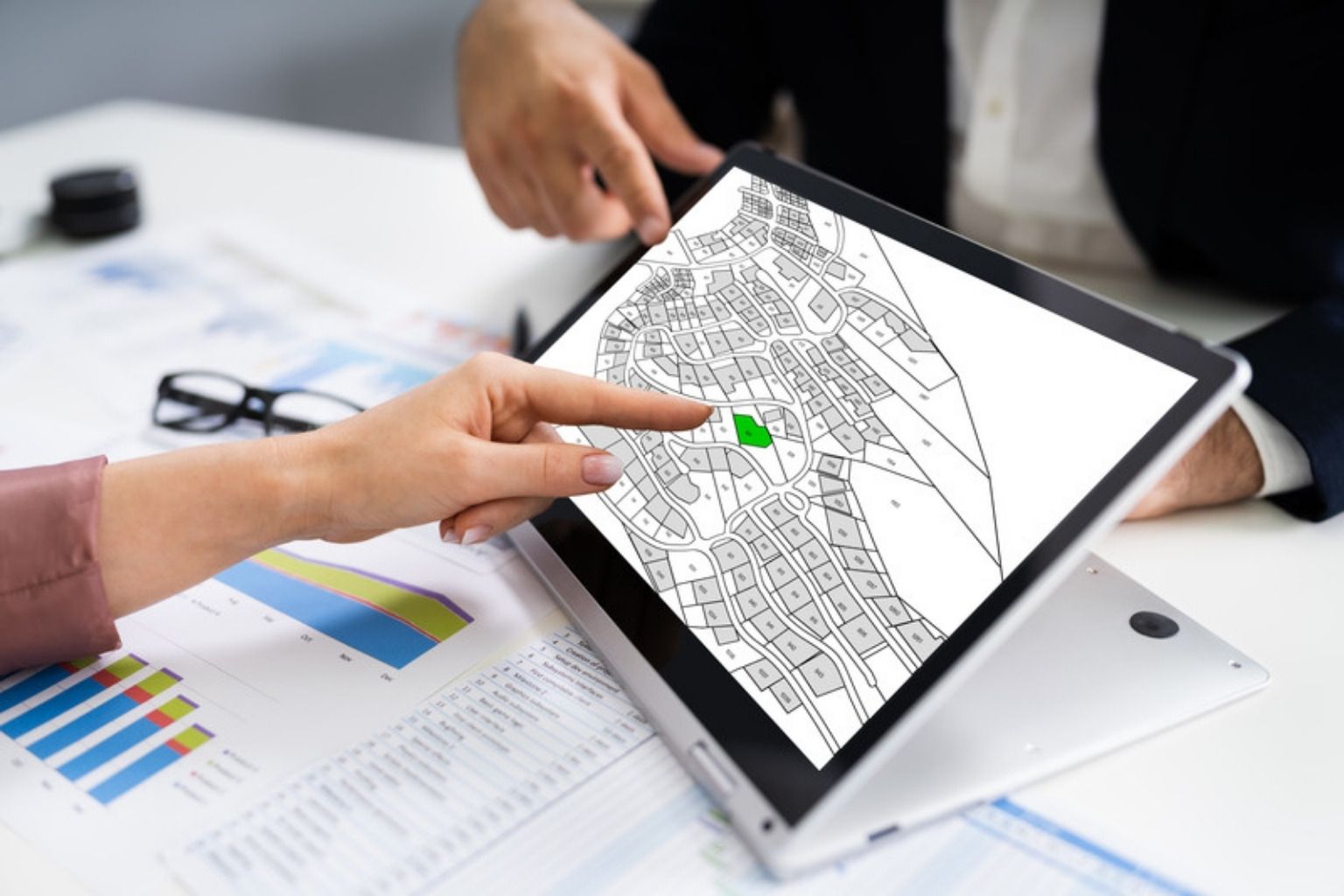To personer peger på et matrikelkort på en tablet ved et mødebord